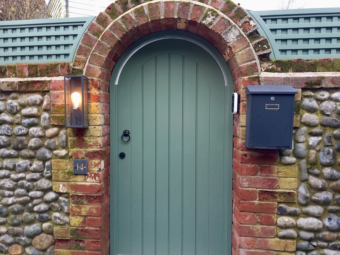 Bespoke arched solid gate with backed square trellis (38mm gap) painted in Gorse Green and with an old brick wall.